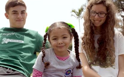 Two volunteers smiling with a kid during a childcare group trip in Costa Rica Happy child smiling with two Projects Abroad childcare volunteers in Costa Rica